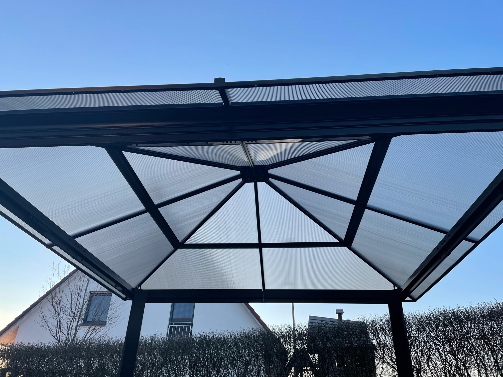 Toiture en polycarbonate alvéolaire couleur Bronze installée sur une structure métallique, idéale pour les pergolas et les abris de jardin, offrant légèreté, résistance et luminosité naturelle.