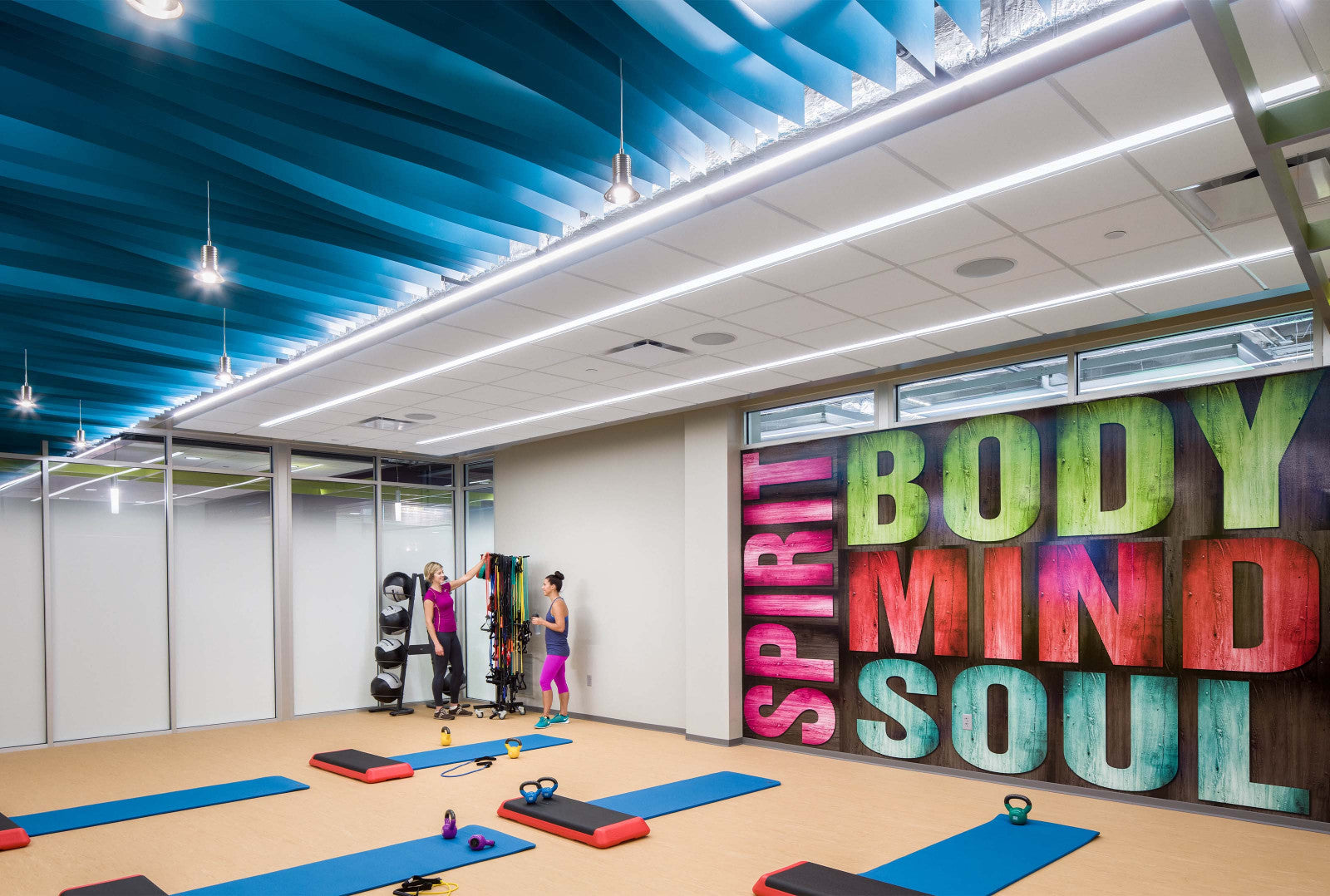 Panneaux en PVC installés au plafond d'une salle de fitness moderne, offrant une isolation acoustique et une esthétique colorée.